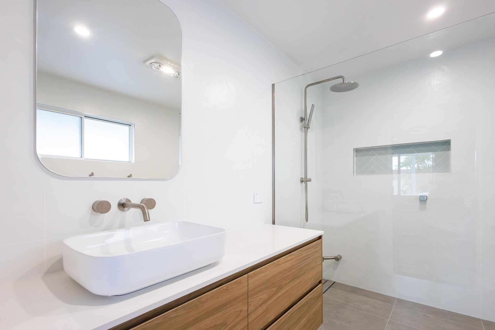 A bathroom with a sink , mirror and walk in shower.