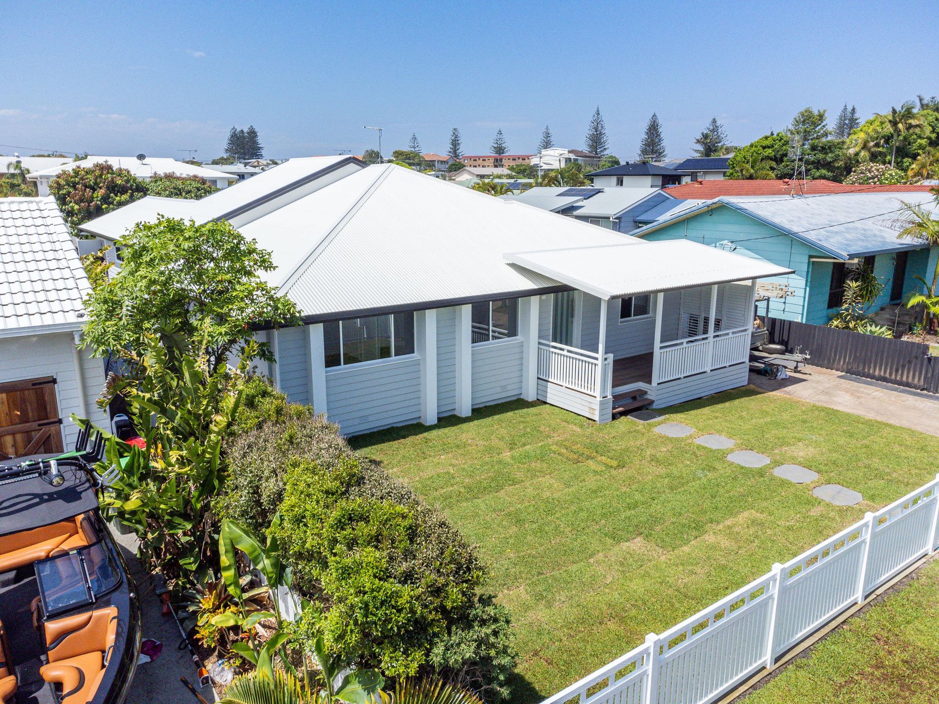 An aerial view of a house with a white fence and a boat in front of it.