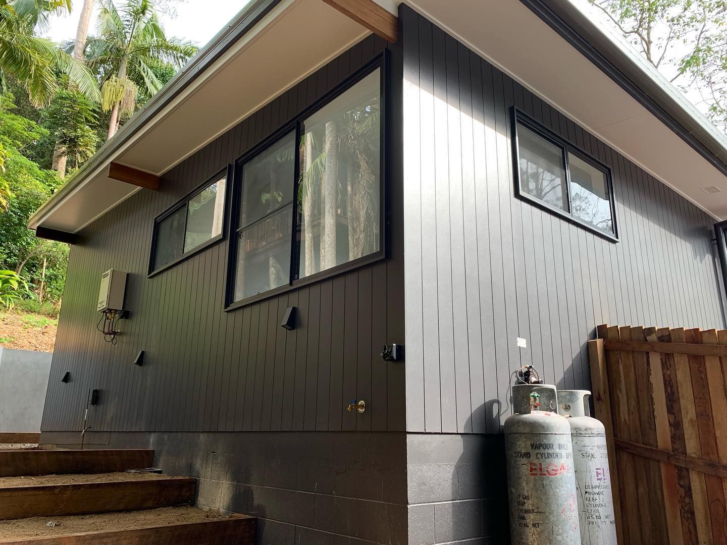 A house with a lot of windows and two gas tanks on the side of it.