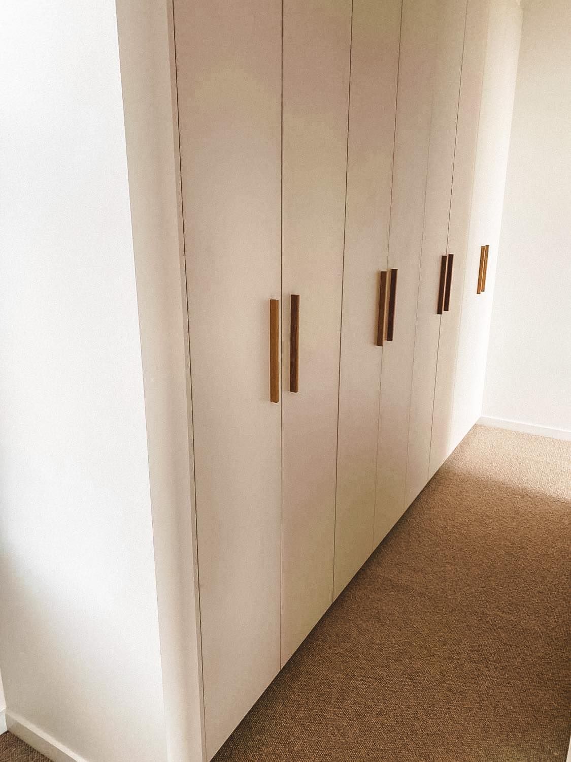 A row of white cabinets with wooden handles in a room.