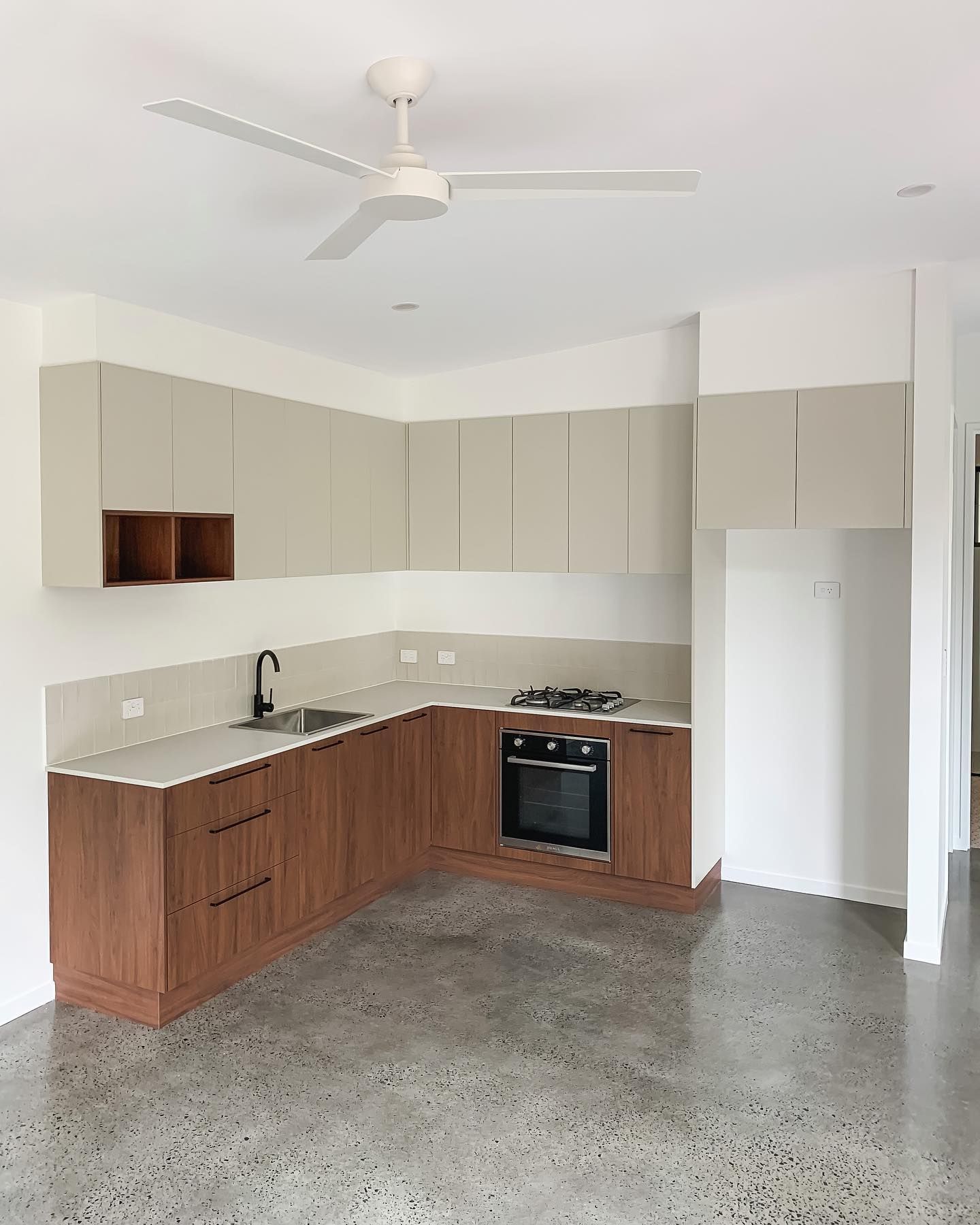 An empty kitchen with wooden cabinets and a ceiling fan