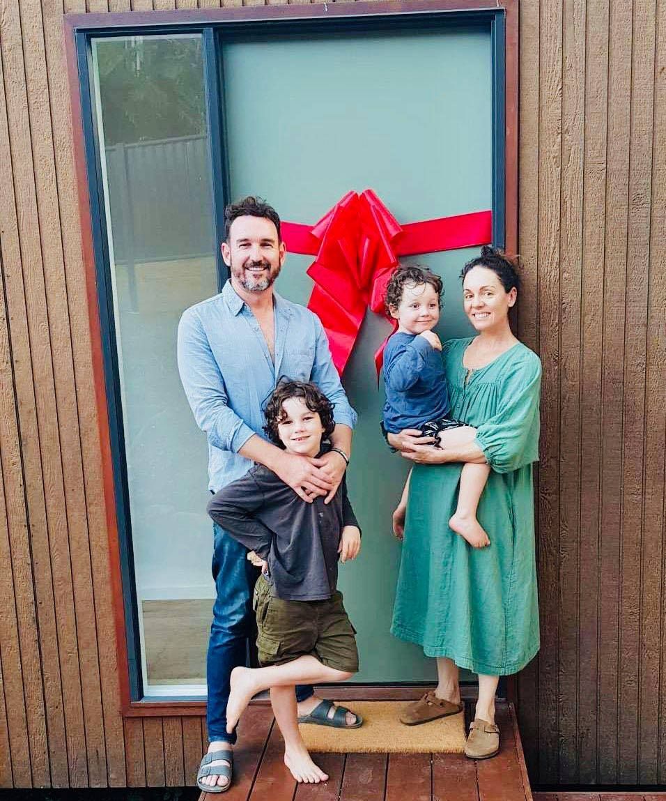 A family is standing in front of a door with a red bow on it.