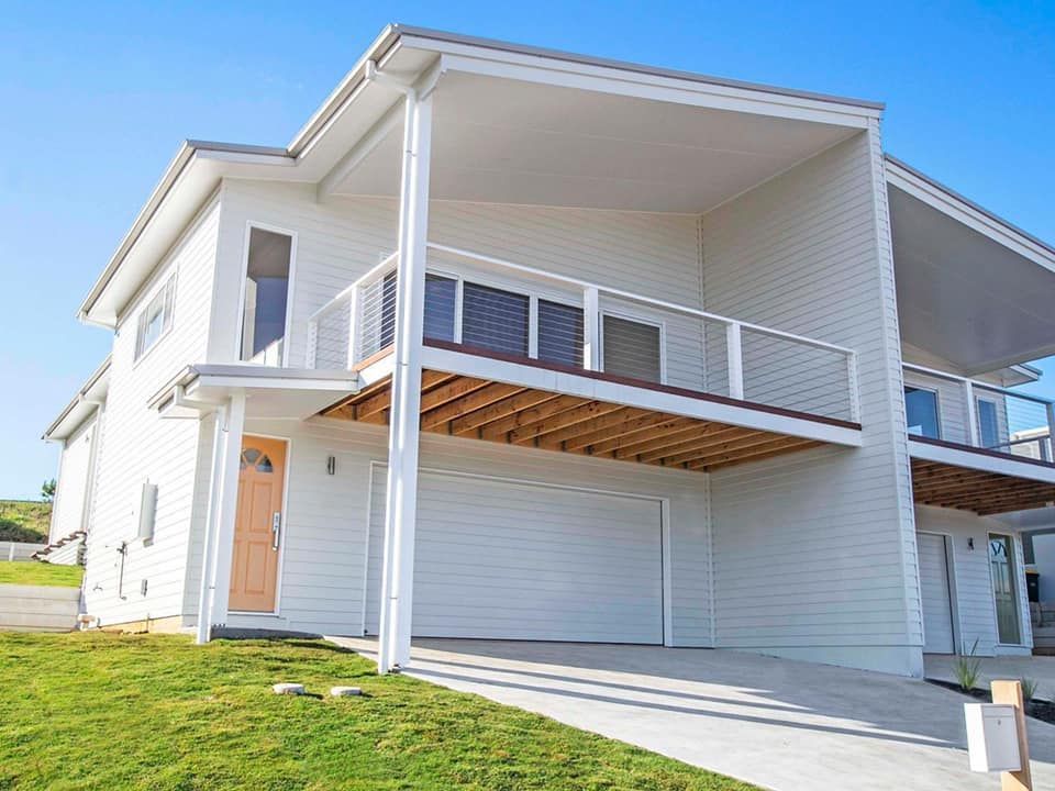 A white house with a balcony and a garage door.