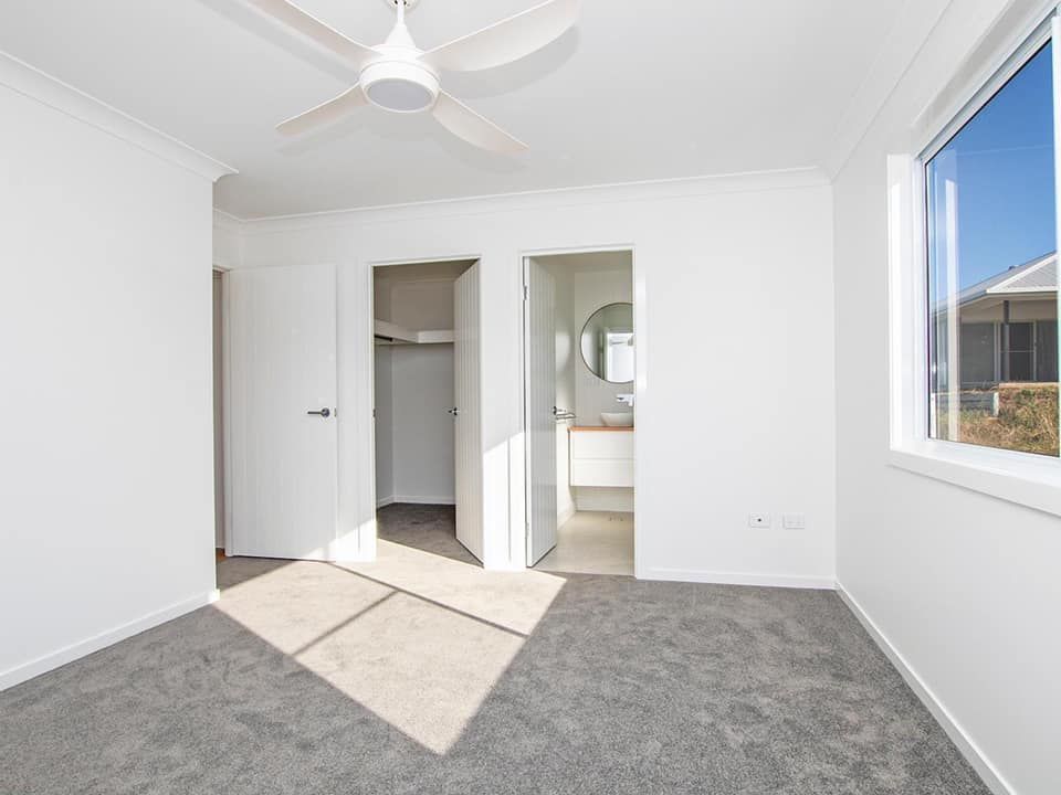An empty bedroom with a ceiling fan and a window.