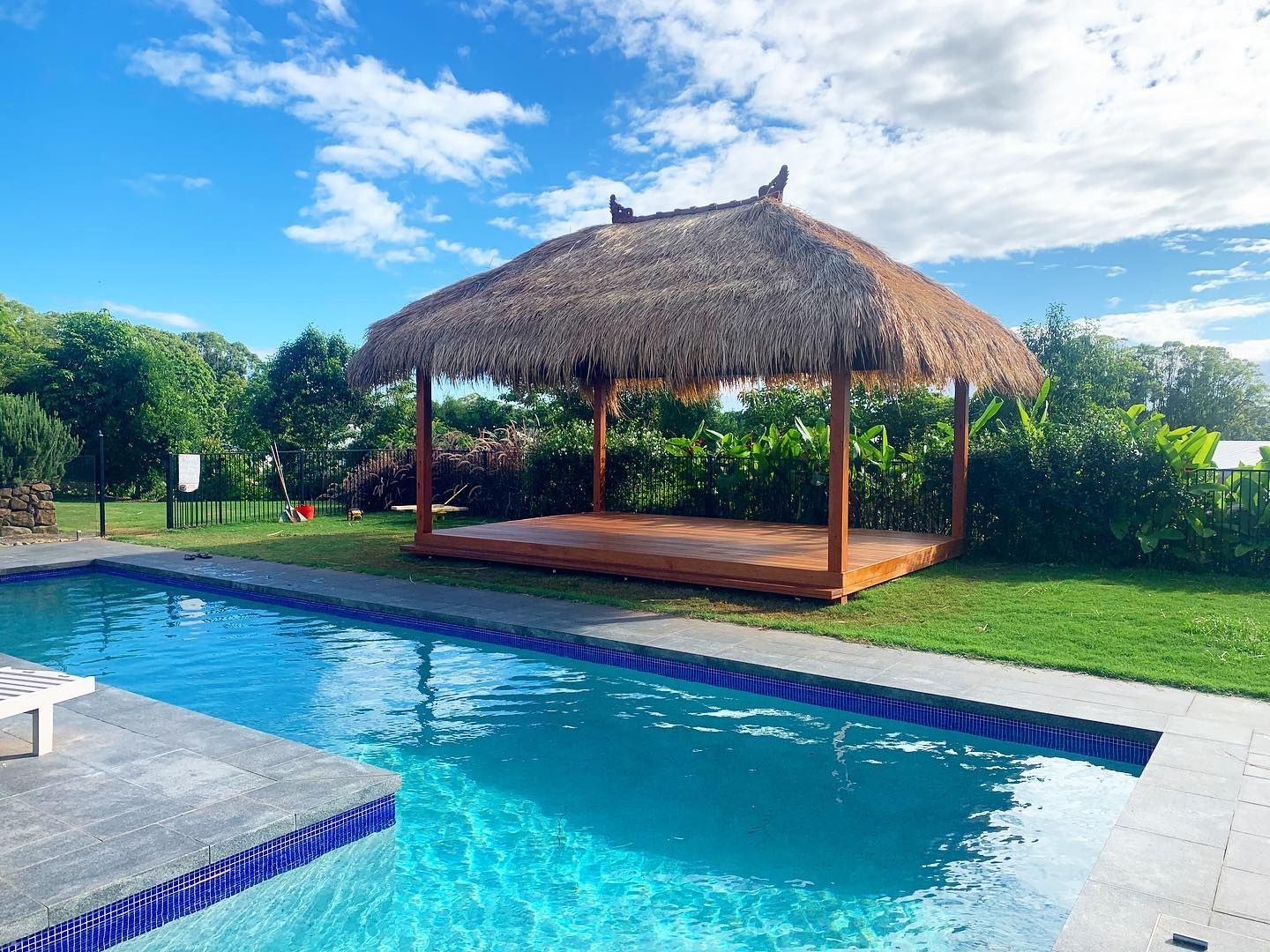 there is a thatched gazebo next to a swimming pool .