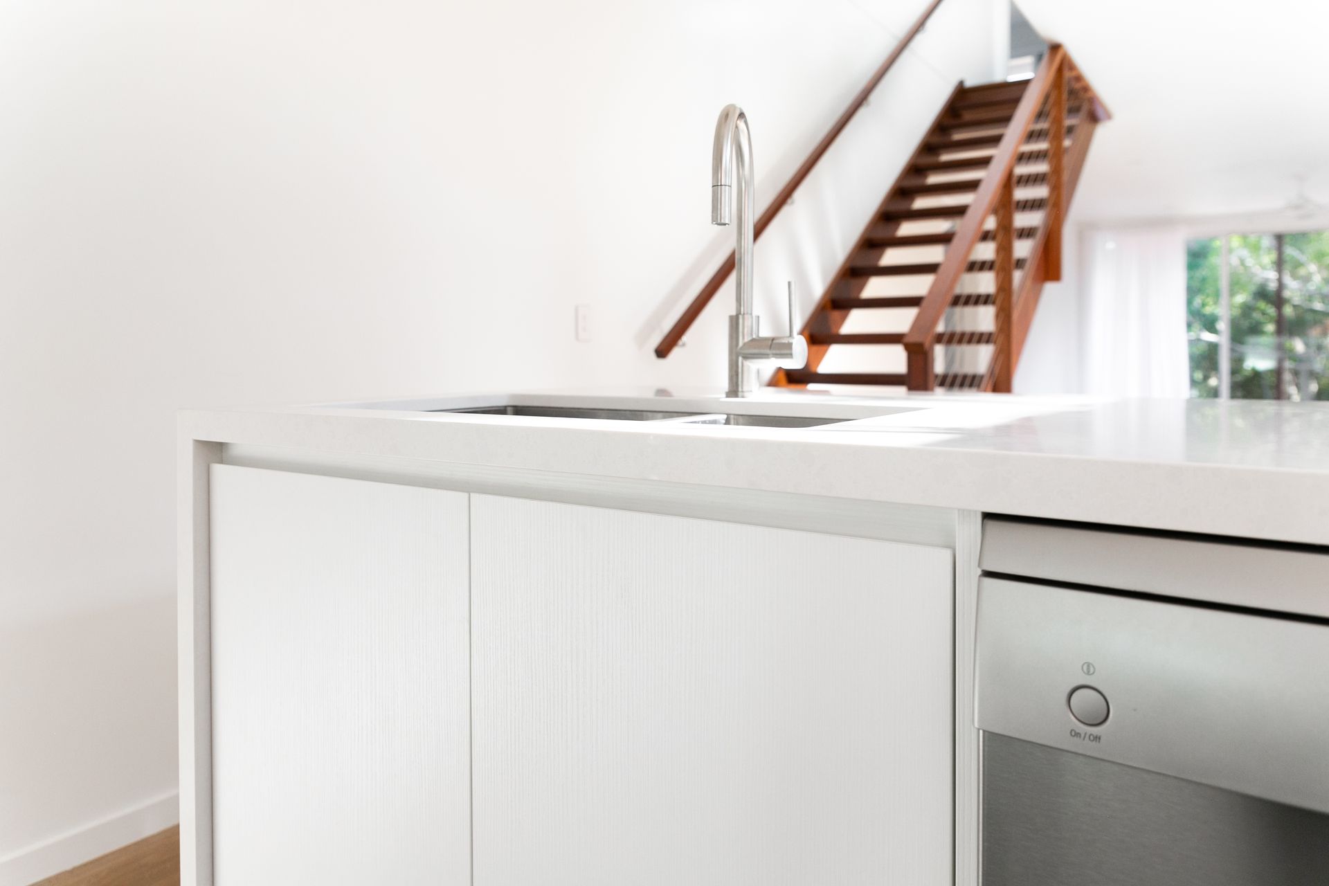 A kitchen with a sink and stairs in the background