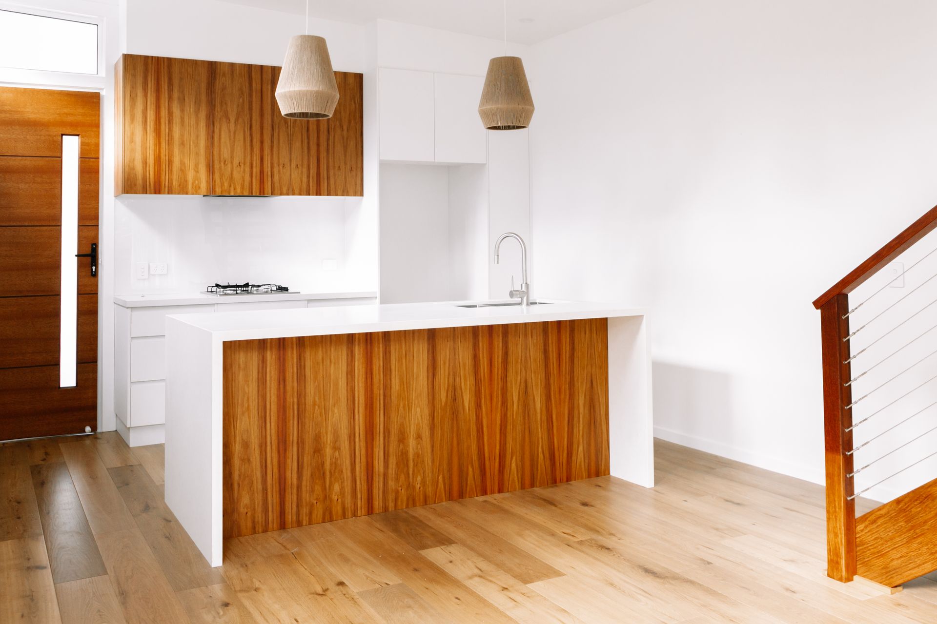 An empty kitchen with a wooden island and stairs.