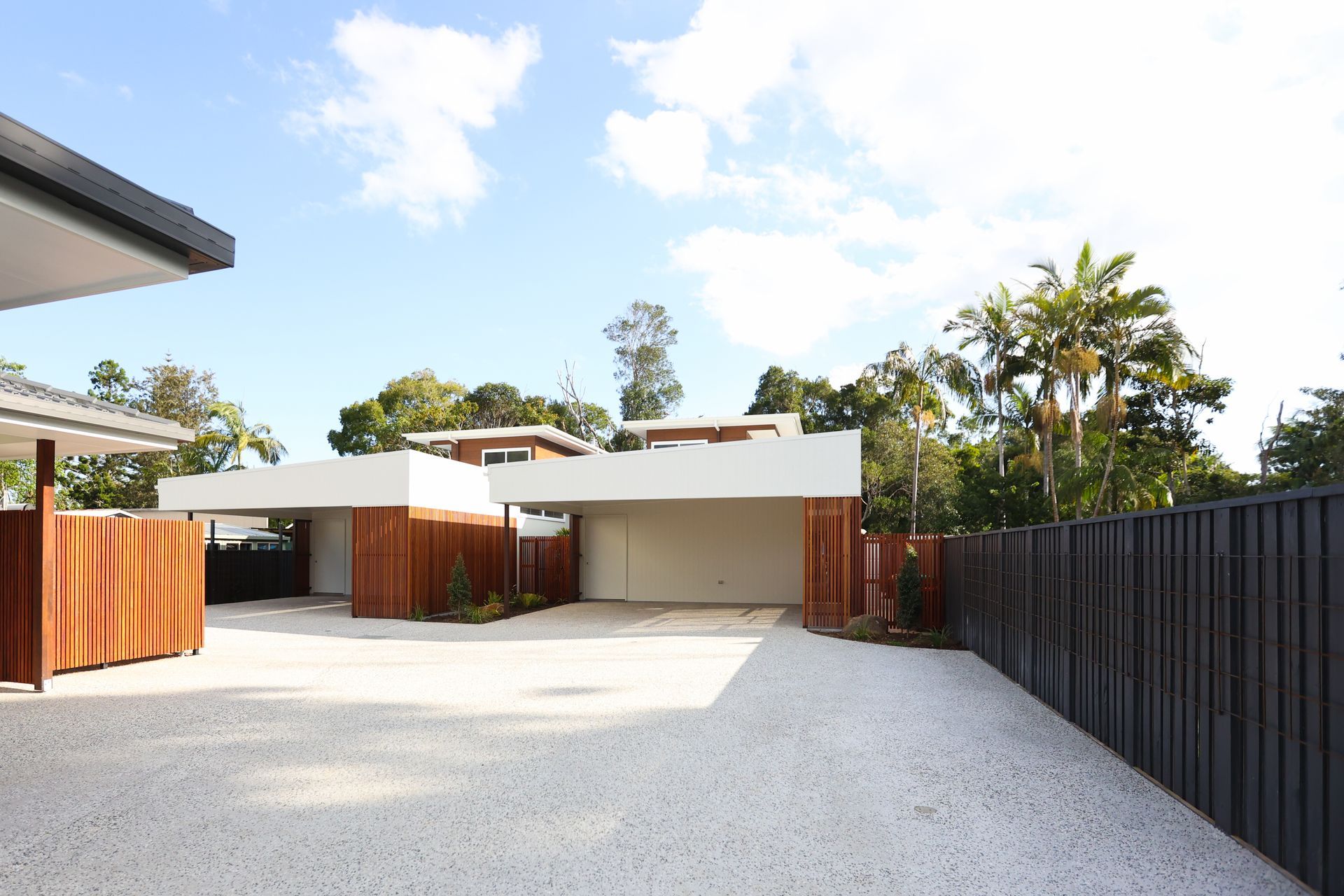 A driveway leading to a house with a black fence