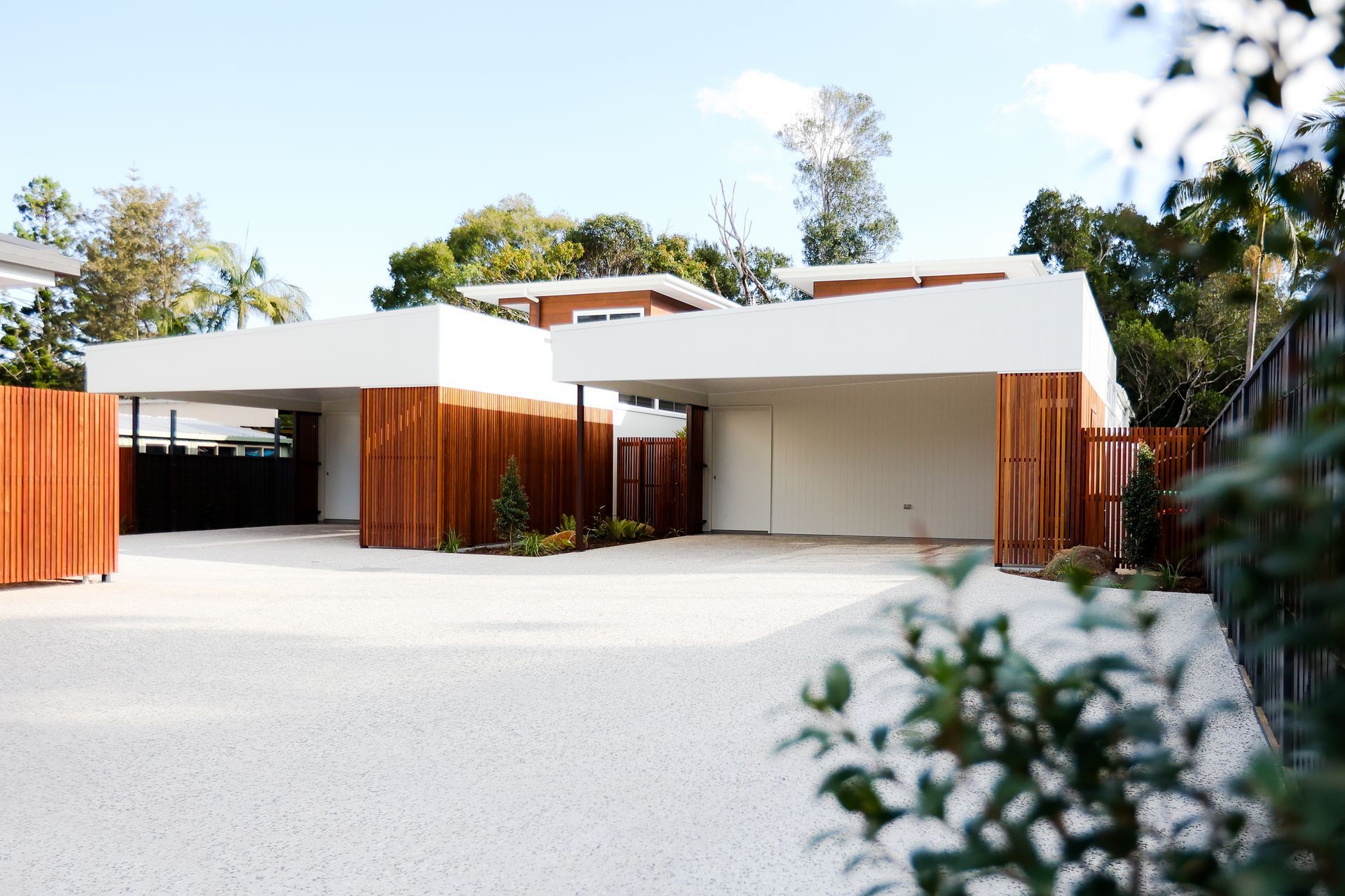 A white house with a wooden fence and a driveway