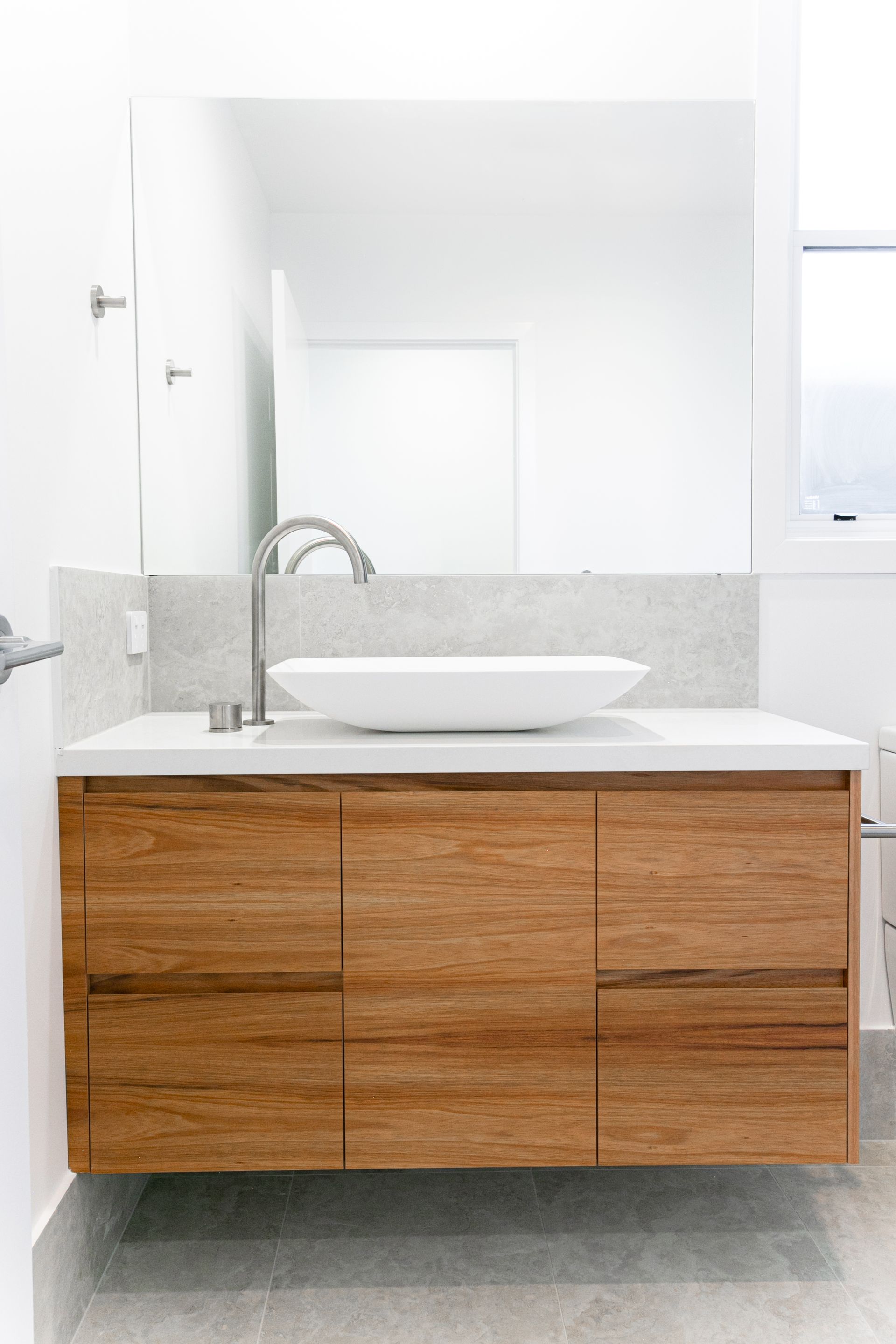 A bathroom with a sink , mirror and wooden cabinets.
