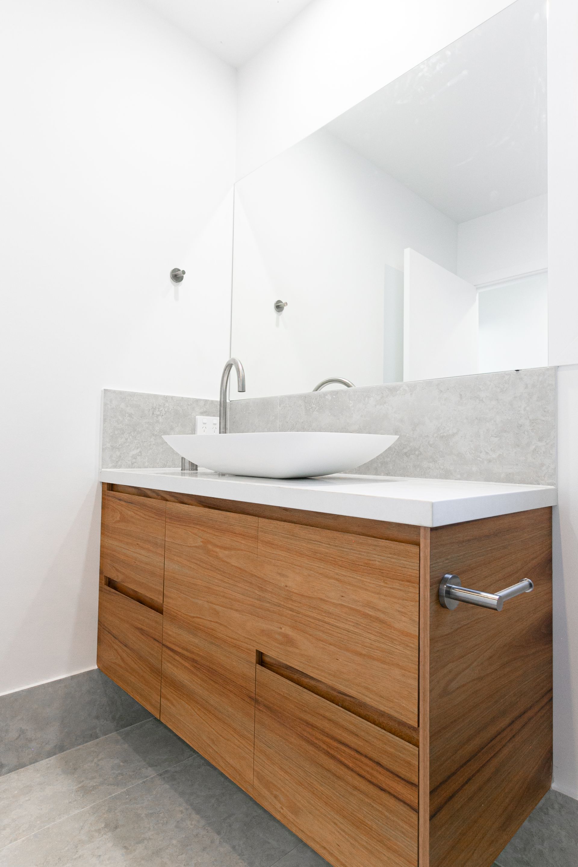 A bathroom with a wooden vanity , sink and mirror.