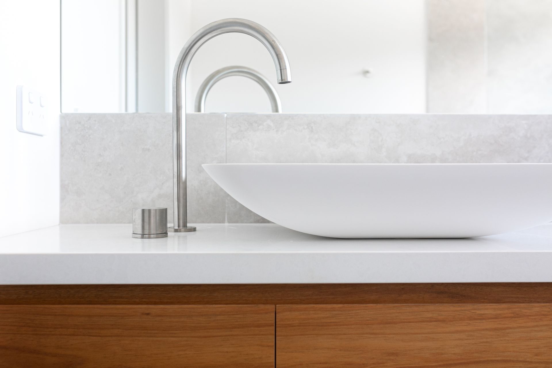 A bathroom sink with two faucets and a mirror.