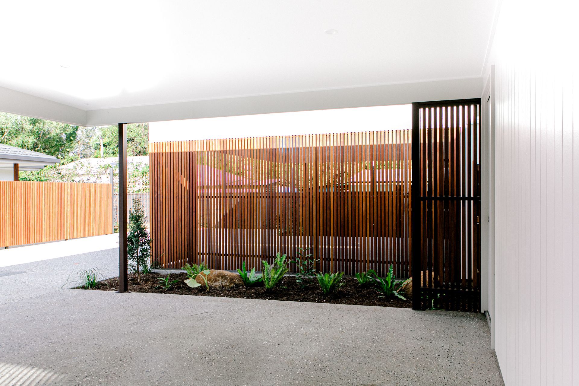 A driveway with a wooden fence and a white wall