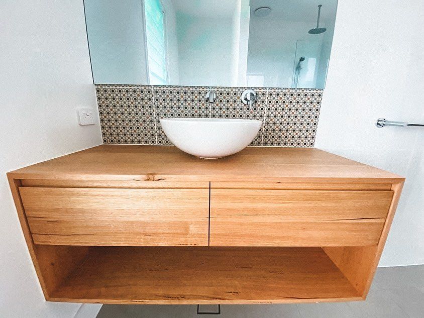 A bathroom with a wooden vanity , sink and mirror.