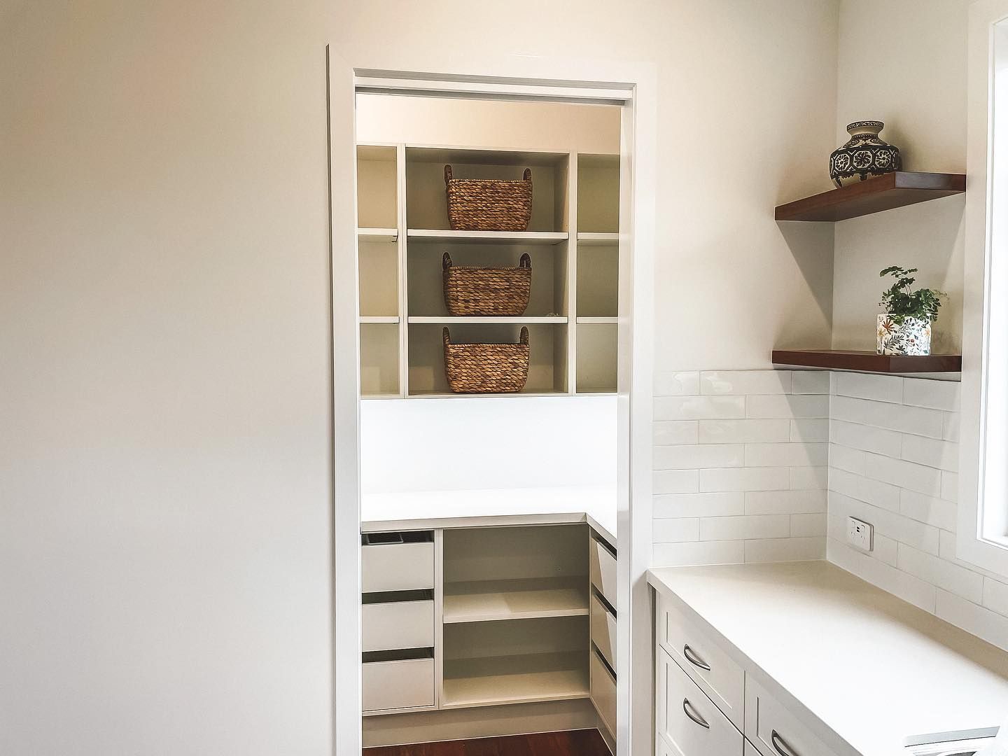 A kitchen with a pantry and shelves and a window