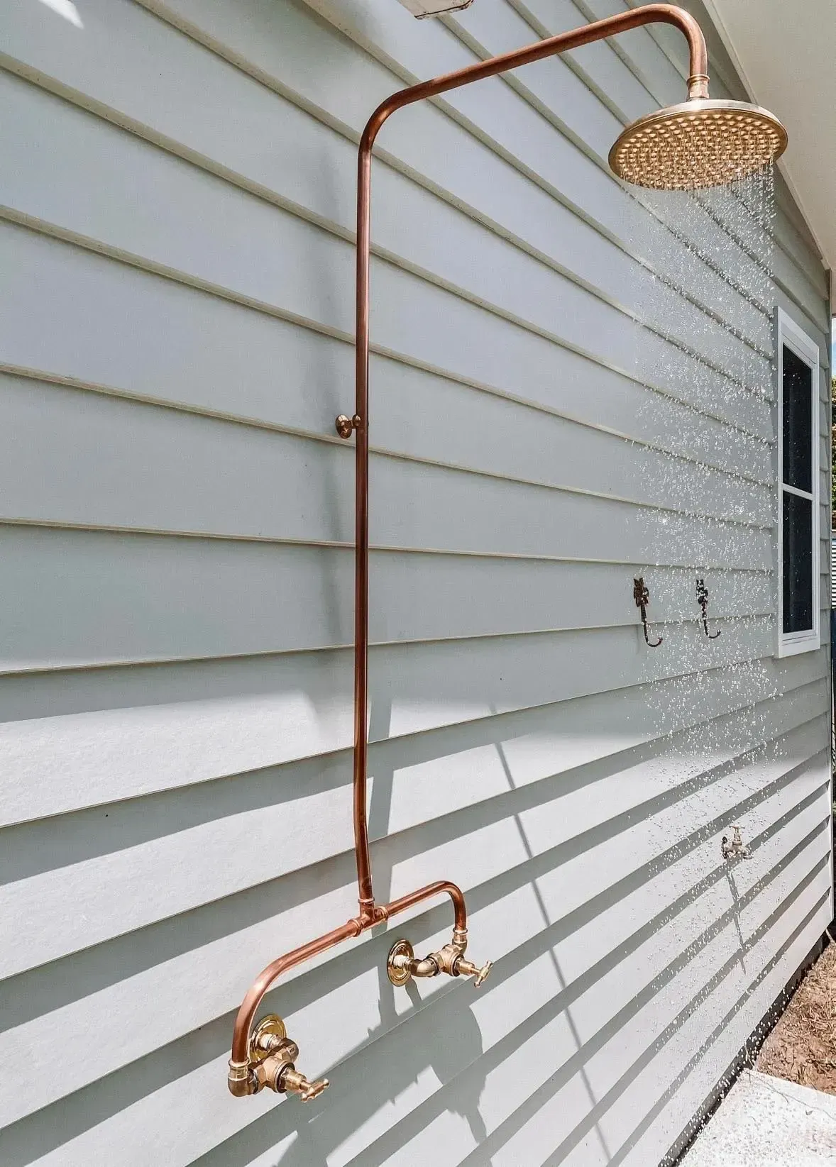 Outdoor living in Tweed Heads — coastal copper outdoor shower on weatherboard wall.
