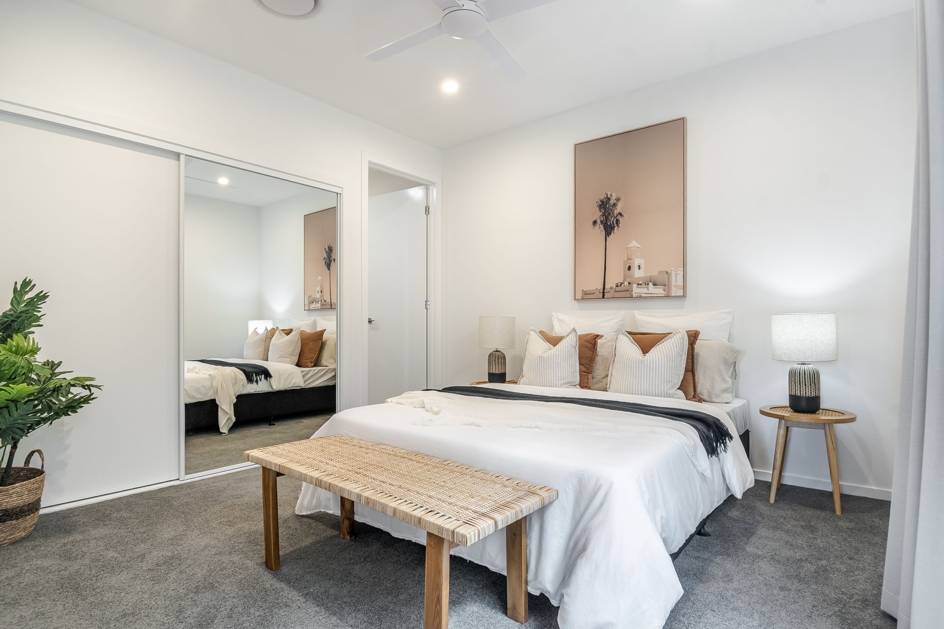 A bedroom with a large bed , a bench , and a ceiling fan.