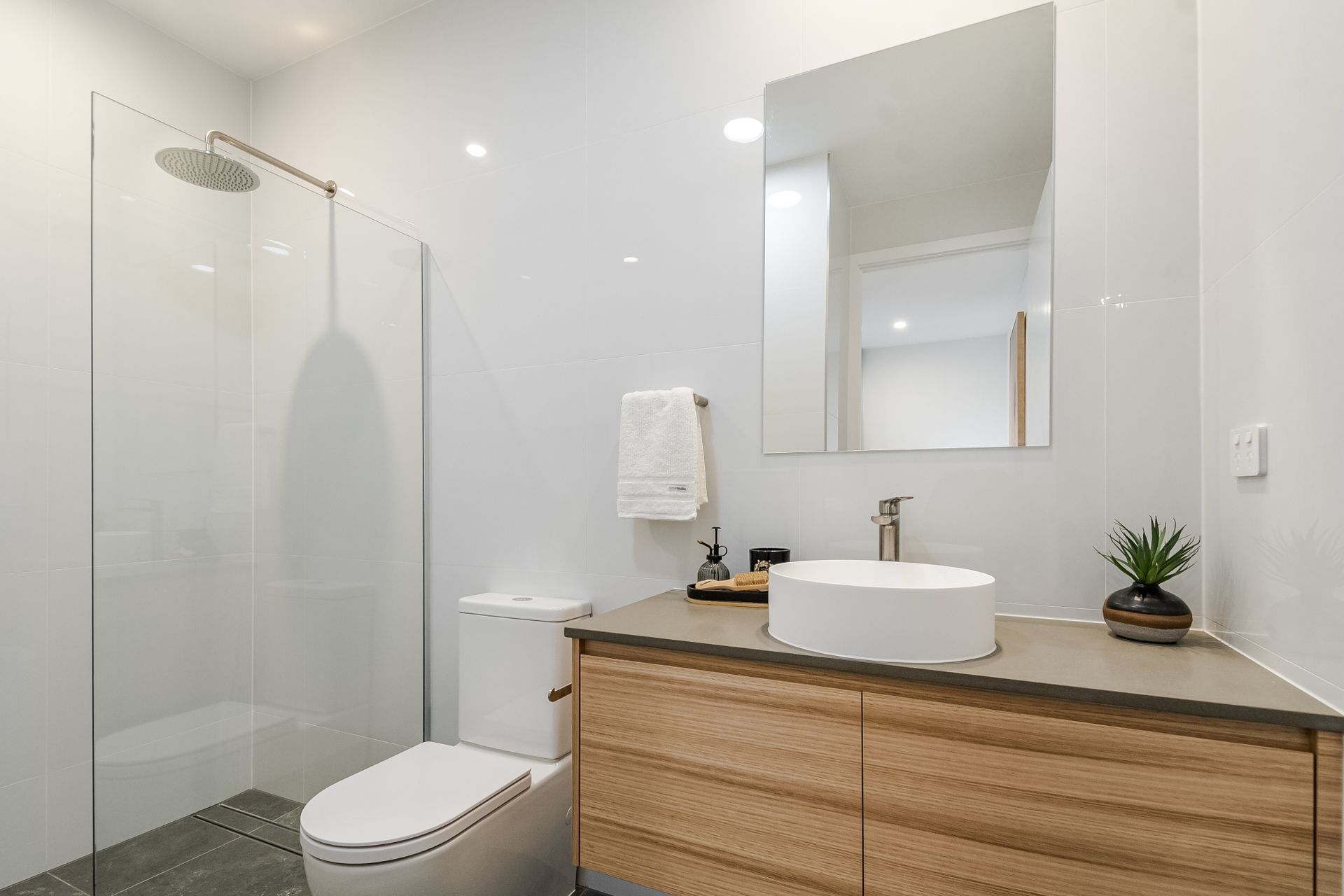 A bathroom with a toilet , sink , mirror and walk in shower.