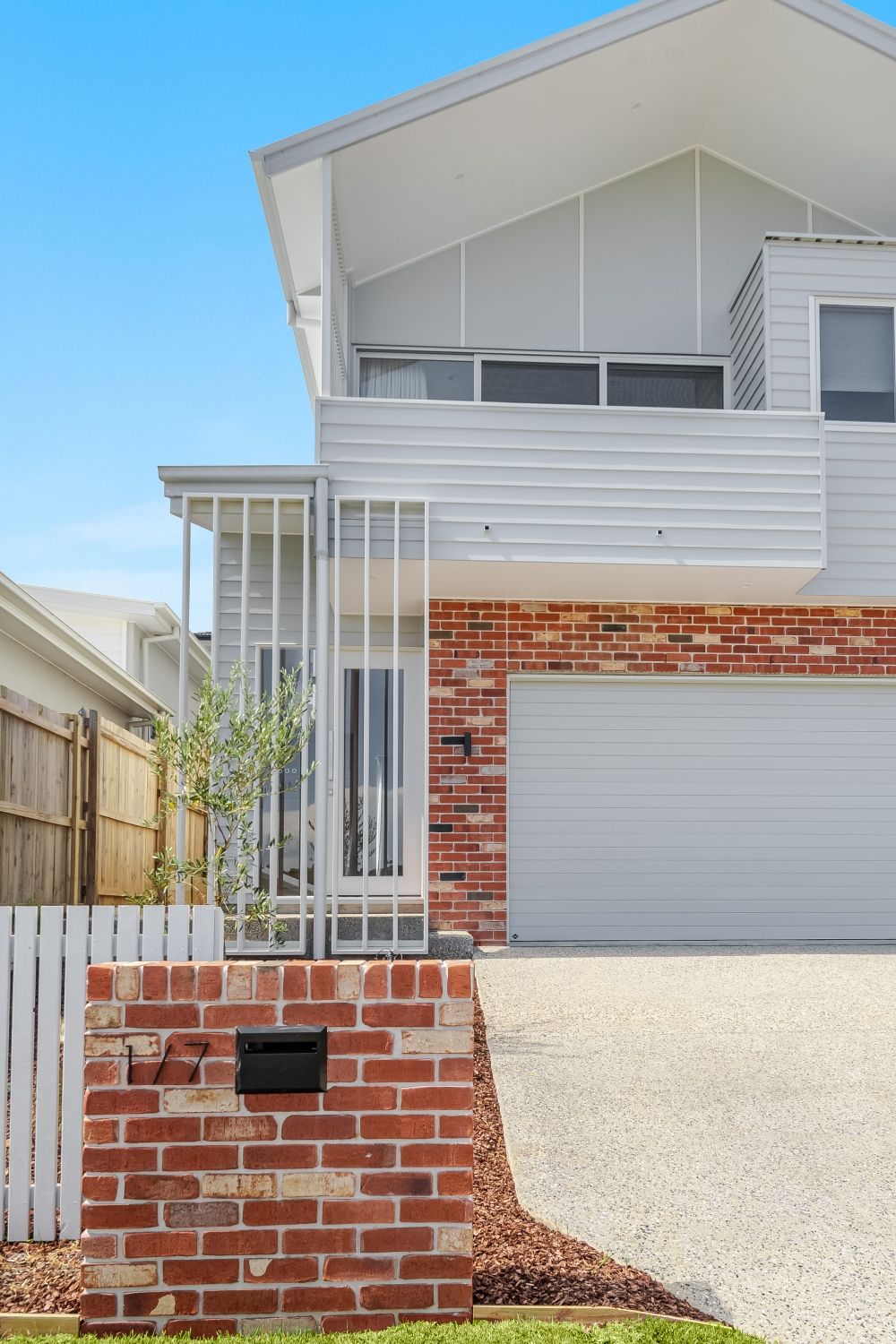 A white house with a red brick wall and a white garage door