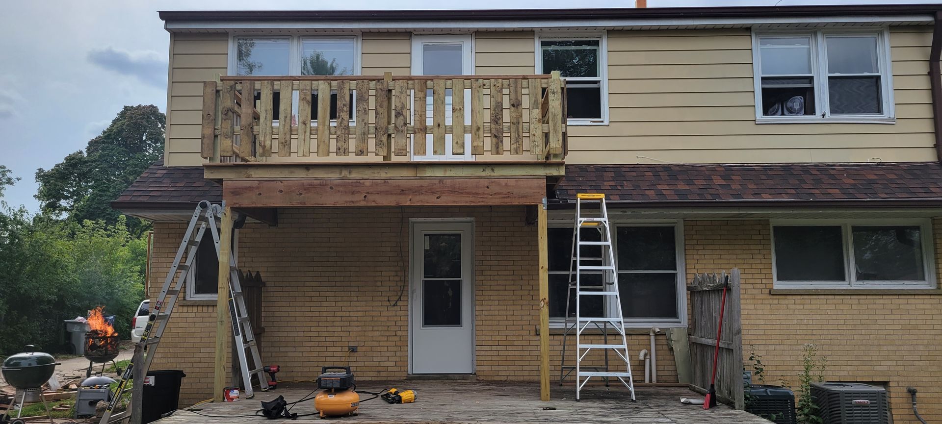 The back of a house with a wooden deck and a ladder.