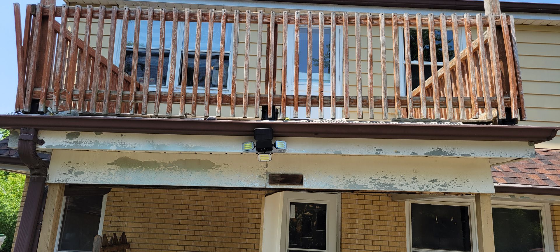 A house with a wooden balcony on the top of it.