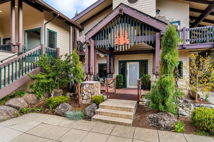 Front entrance of a modern townhouse with steps, stone accents, and landscaped greenery
