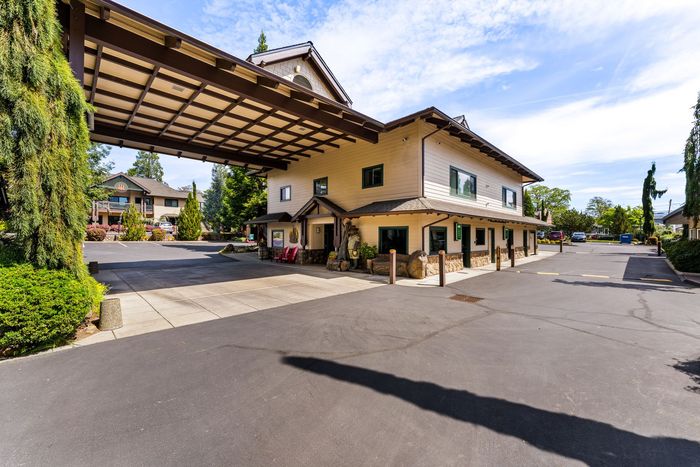 Luxury hotel entrance with covered driveway, beige building, and clear blue sky