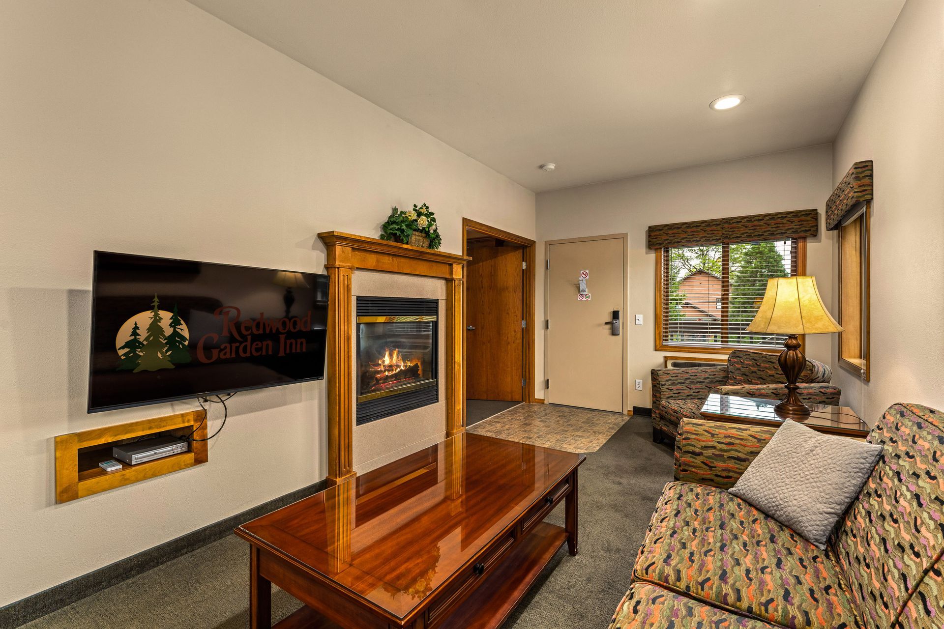 Modern living room with fireplace, wall-mounted TV, sofa, coffee table, and window seat