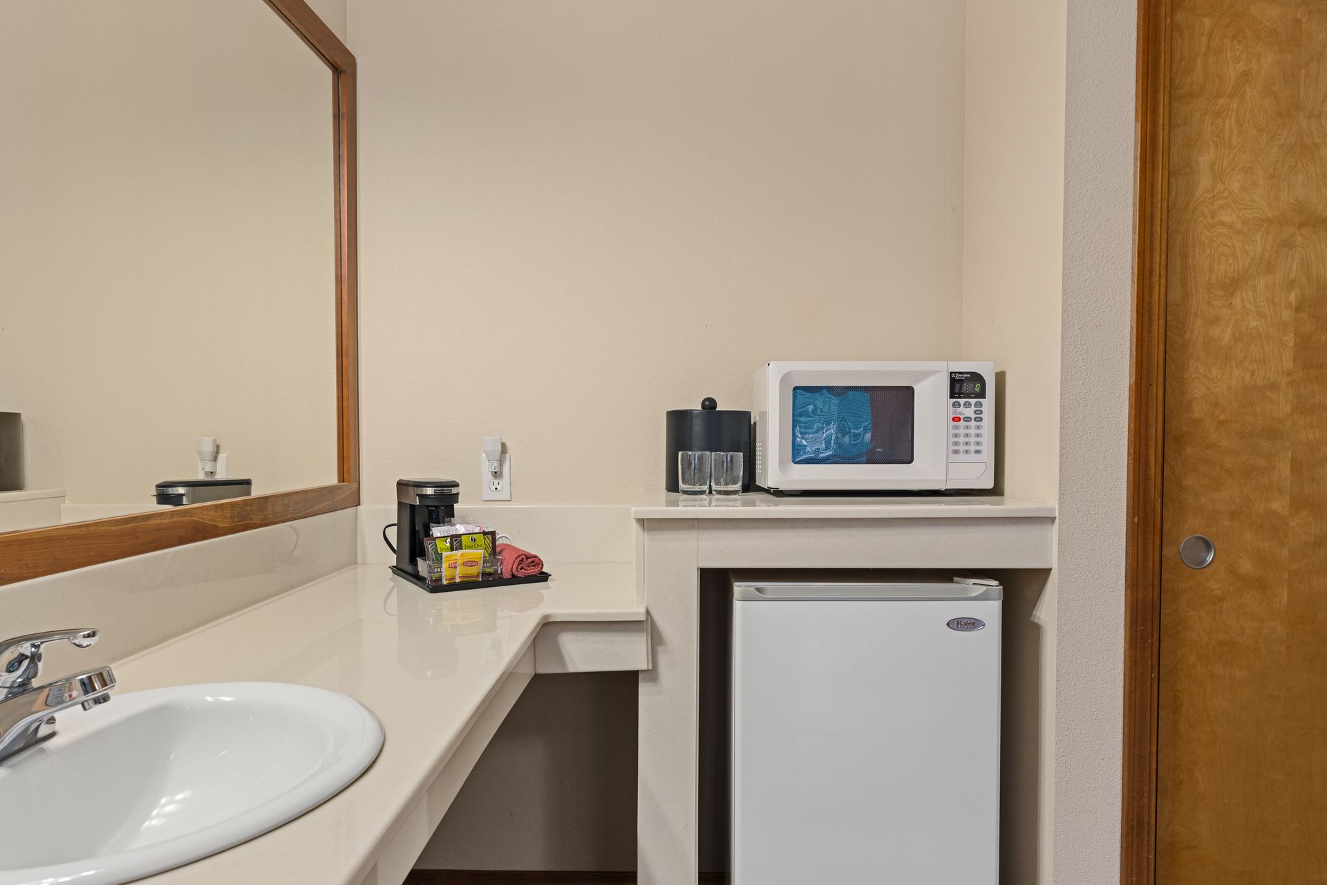 Motel vanity area with sink, mirror, mini fridge, microwave, and coffee maker