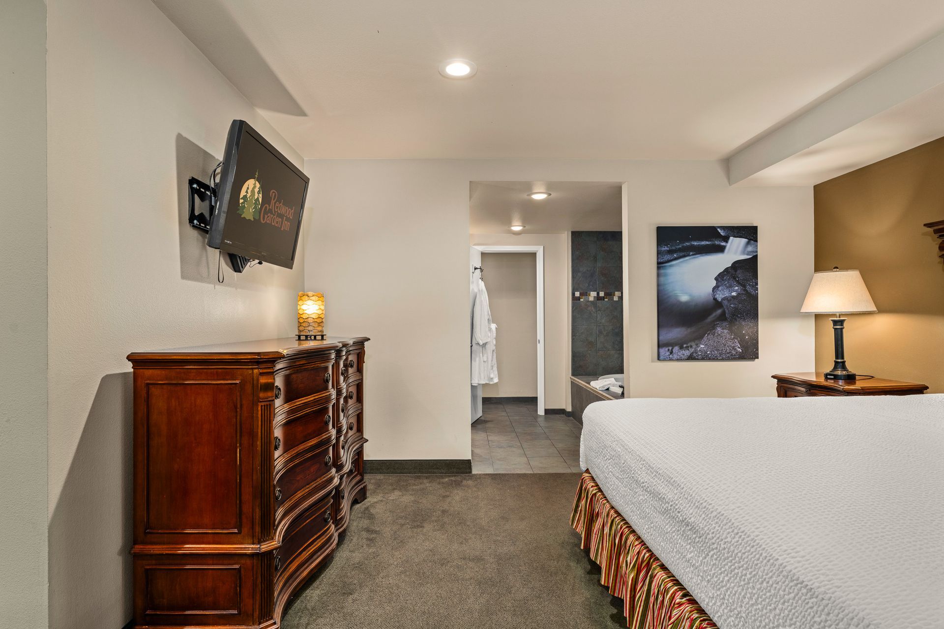 Bedroom with dresser, wall art, and bed in a bright, modern hotel room