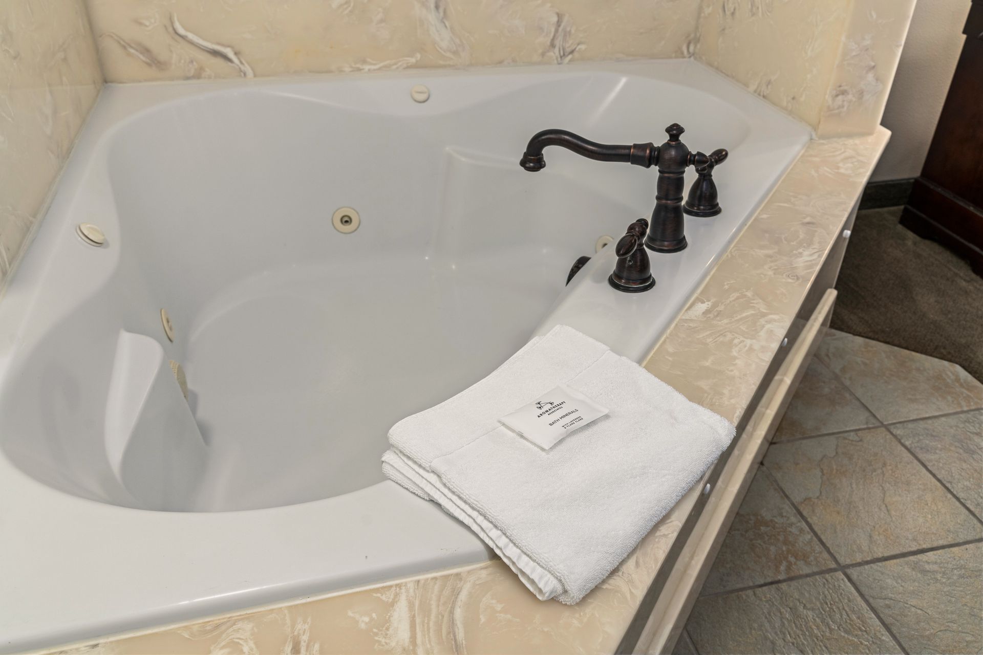 Bathroom bathtub with dark faucet and folded white towels on the ledge