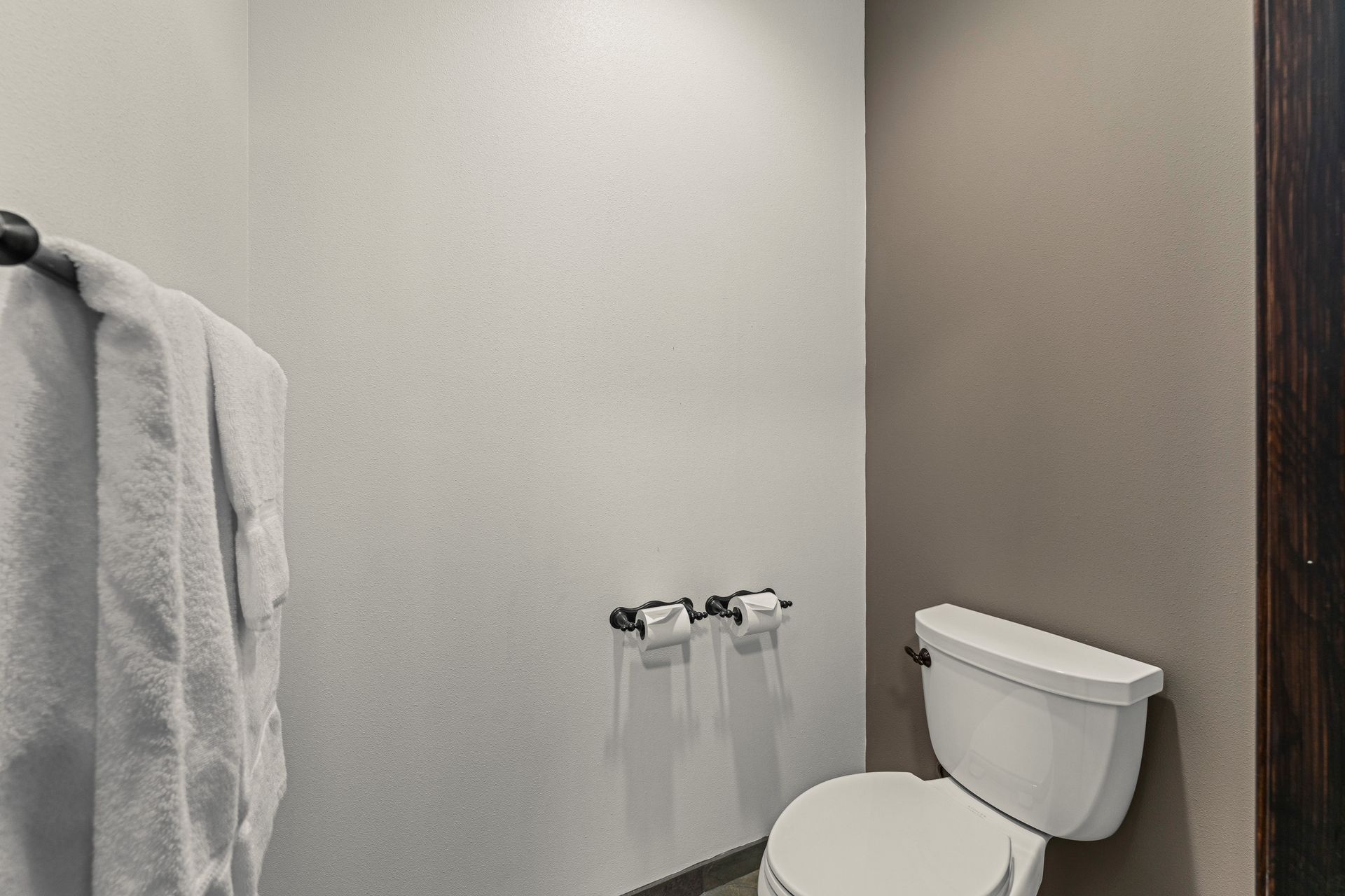 Small bathroom with white walls, a toilet, and a towel hanging on the left.