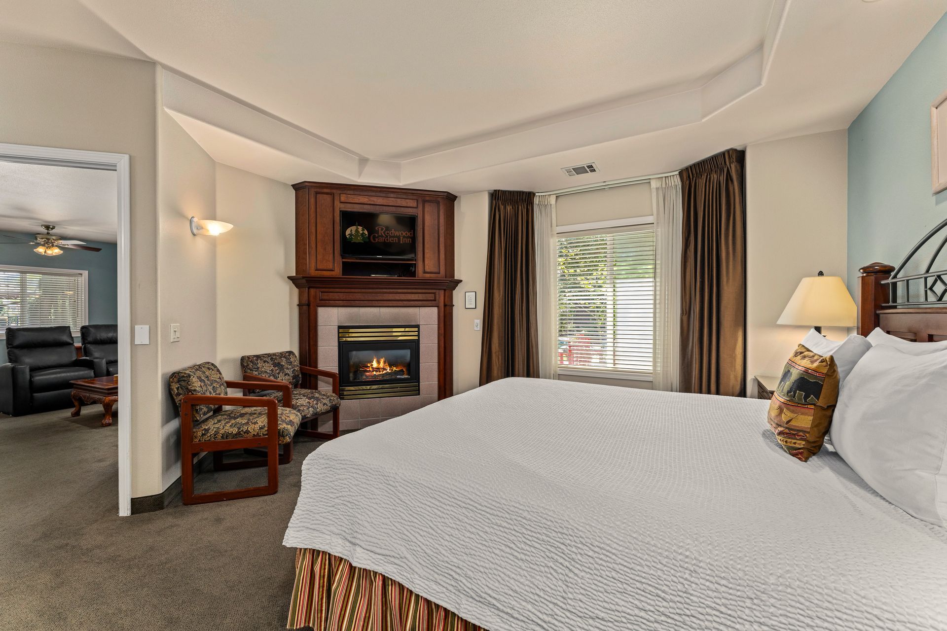 Cozy bedroom with fireplace, king bed, desk, and window view