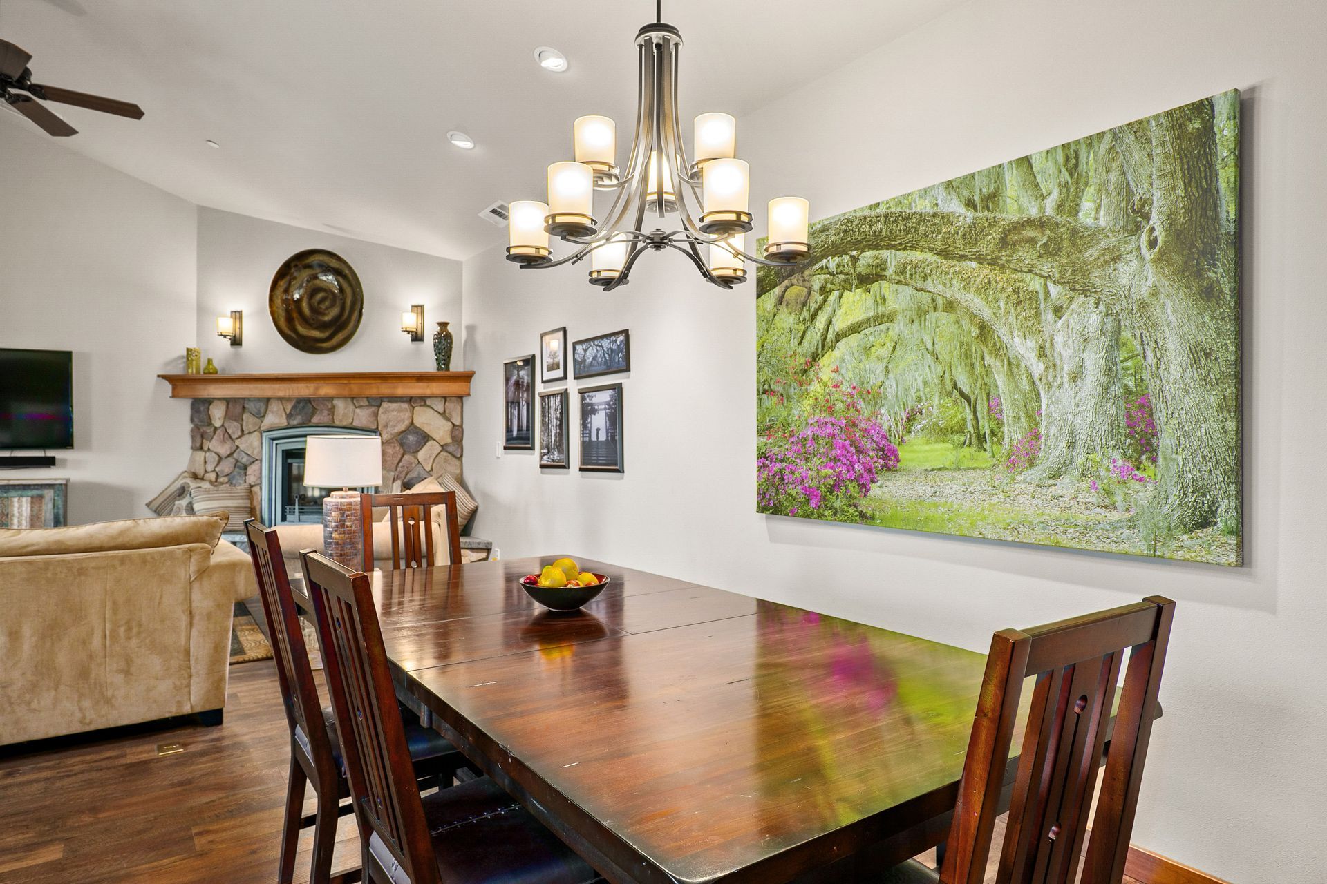 Dining room with dark wood table, chandelier, and large floral wall art in a bright open-plan home