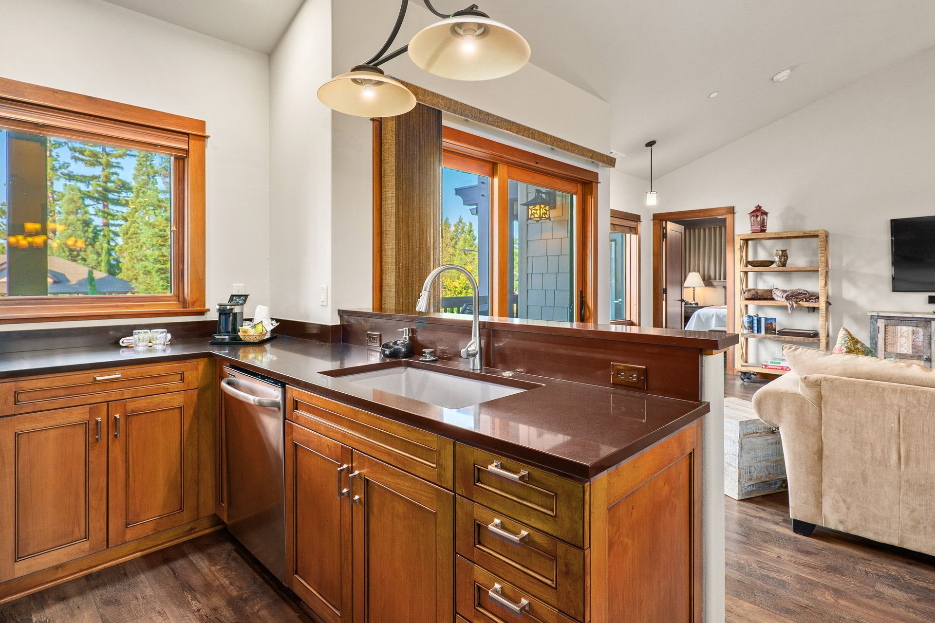 Wooden kitchen island with dark countertops, pendant lights, and large windows in a bright open-plan home