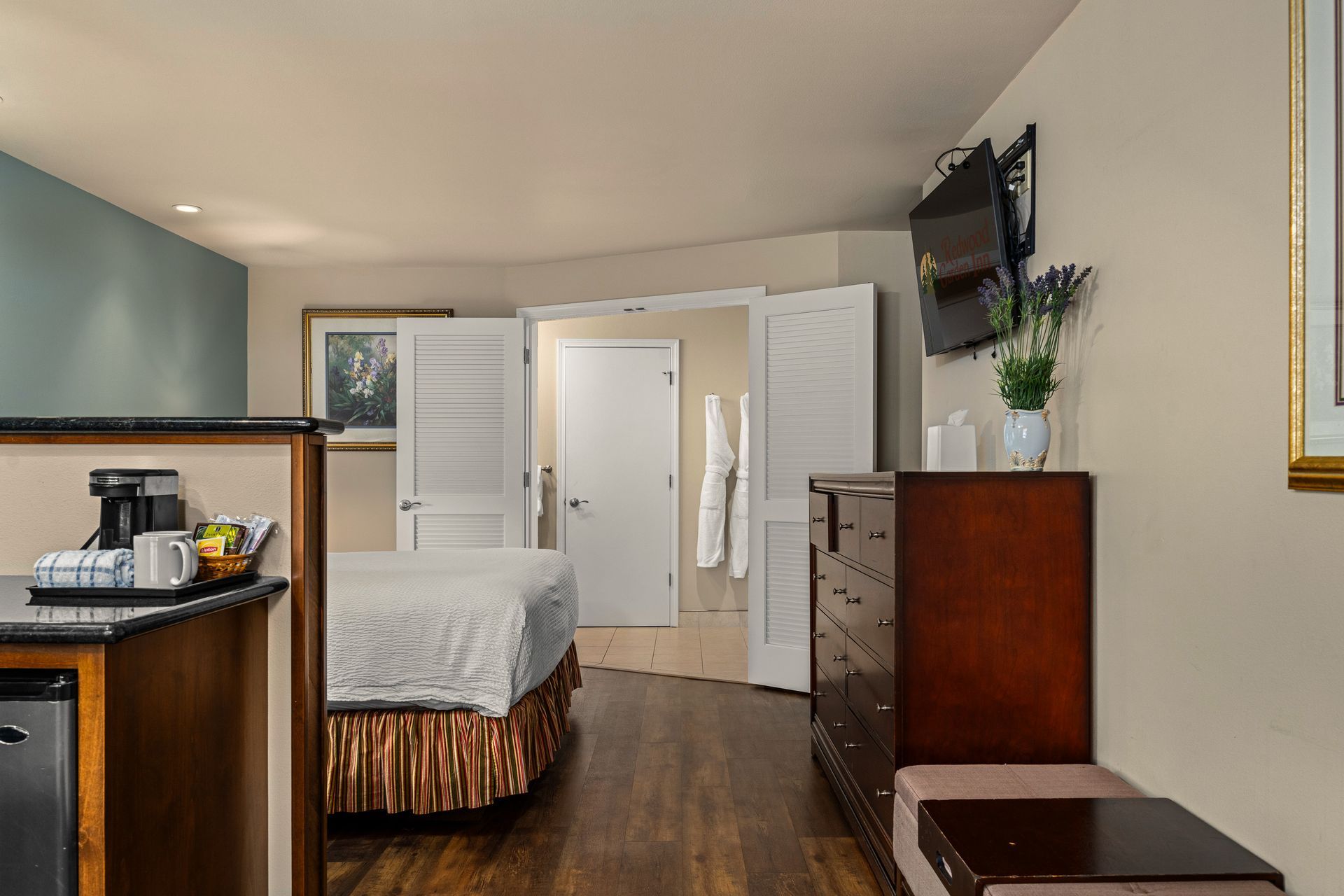Bedroom with bed, dresser, and open double doors leading to a bathroom or closet