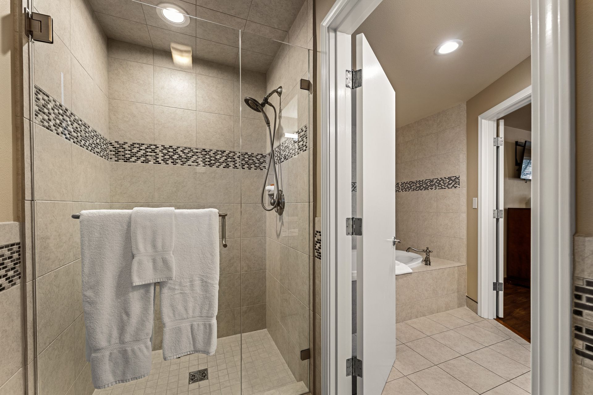 Modern tiled bathroom with glass shower and towel rack