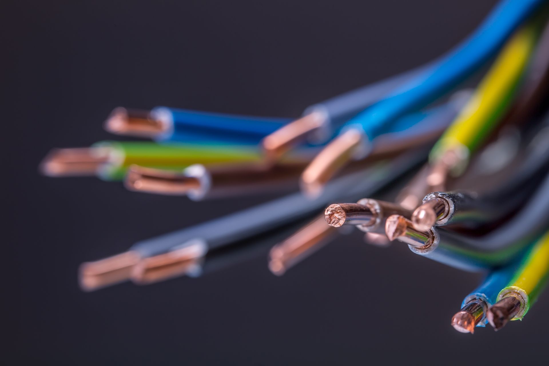 Multicolored electrical wires with stripped copper ends on a dark background