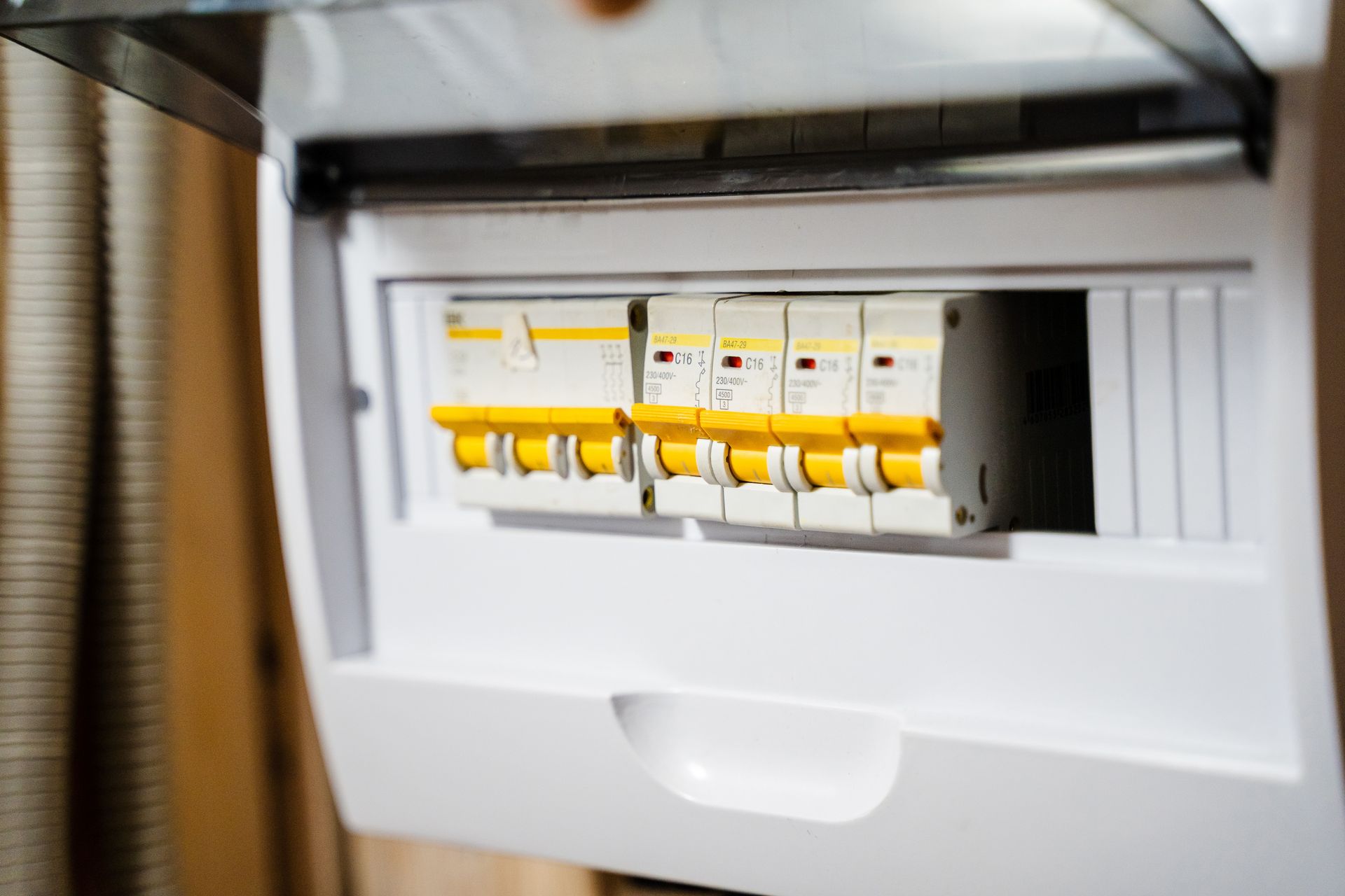 Open electrical breaker panel with yellow switches in a white wall-mounted box