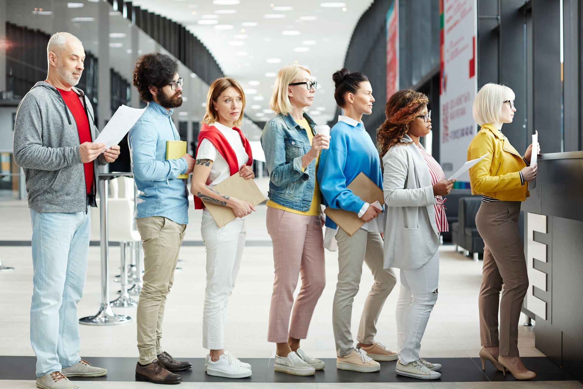 People standing in line at a service counter in a bright office lobby