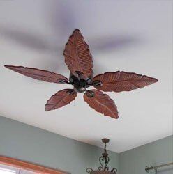 Ceiling fan with large reddish-brown leaf-shaped blades in a room with a light ceiling and wall