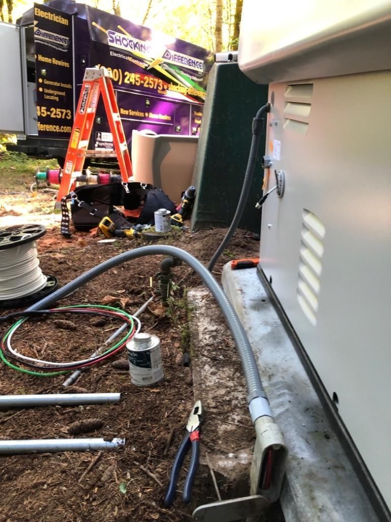 Utility work area with orange ladder, cables, and tools beside a building wall