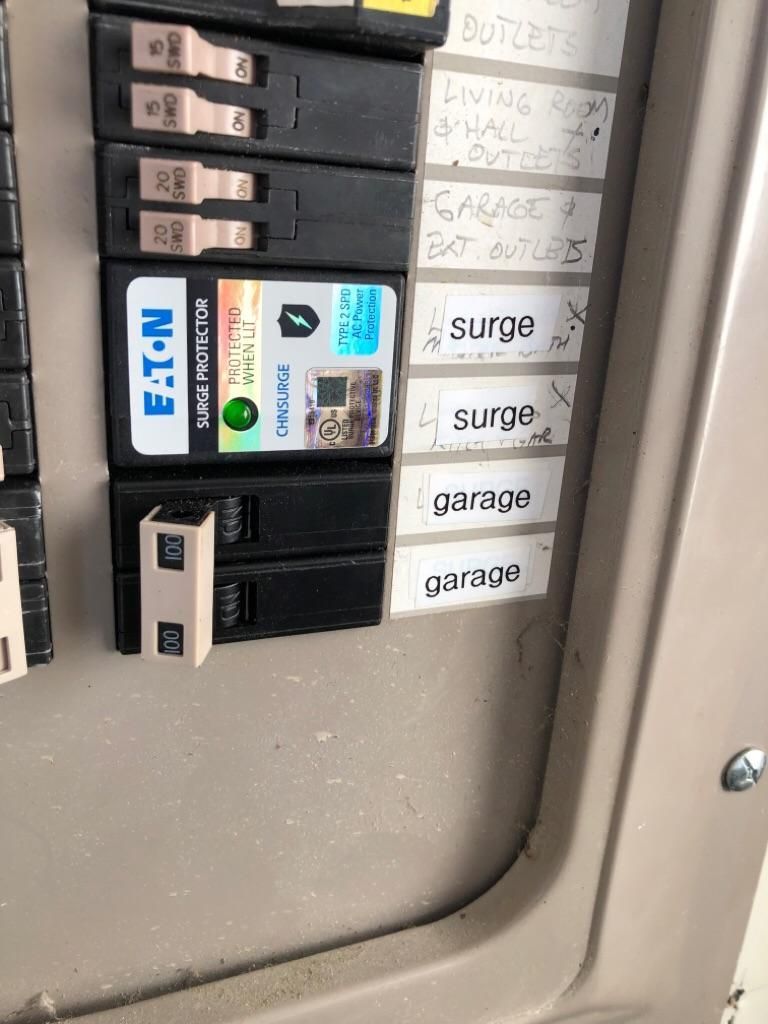 Electrical breaker panel with labeled switches and circuits, including surge and garage labels.