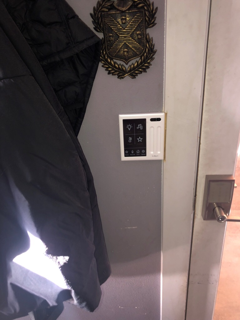 Wall with light switch panel, decorative wall plaque, and a coat hanging by the door.