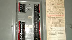 An open electrical breaker panel with multiple switches and a circuit directory label attached to the inside door.