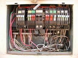 An open electrical breaker panel with various colored circuit breakers and a complex network of internal wiring.