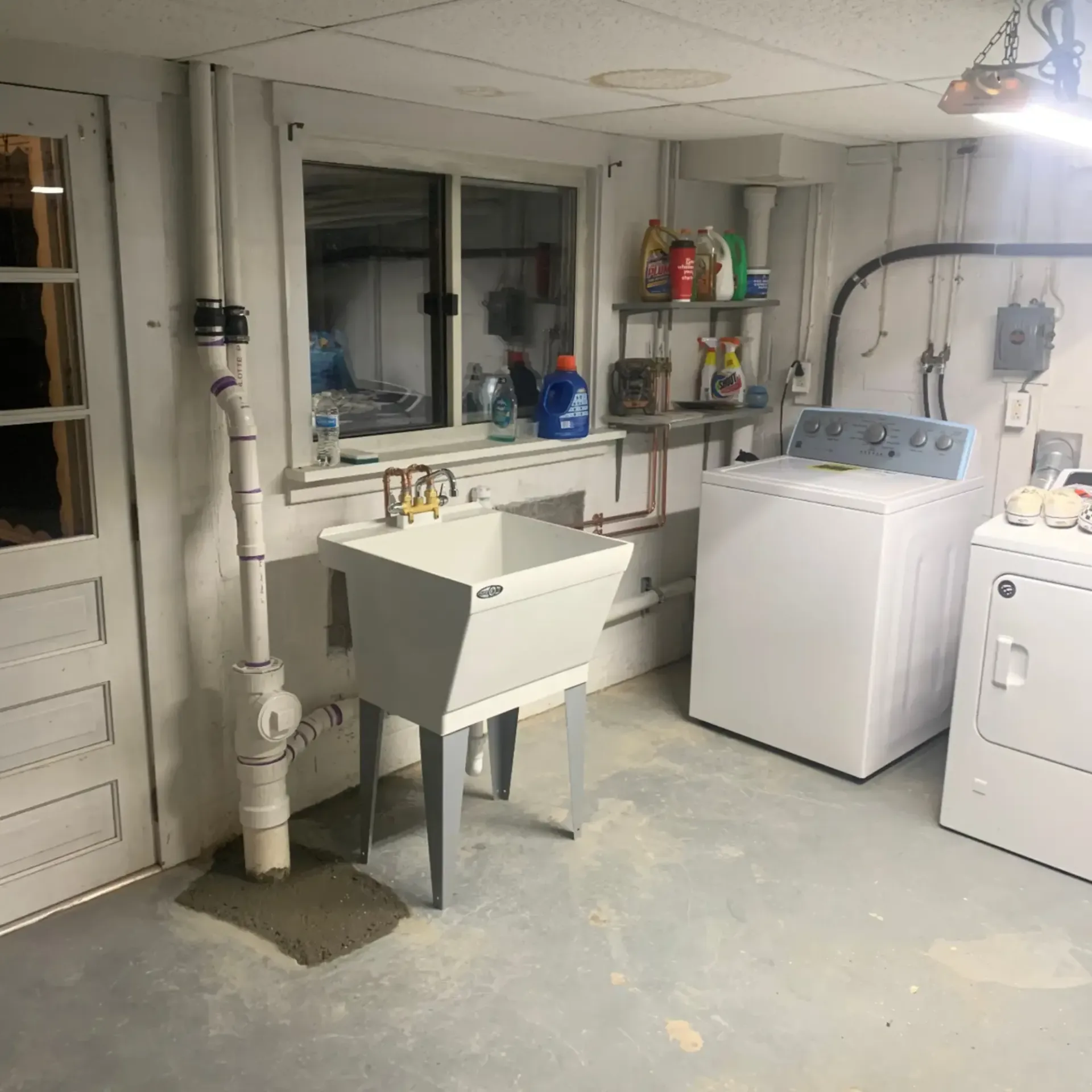Laundry room with a utility sink, washing machine, dryer, and window.