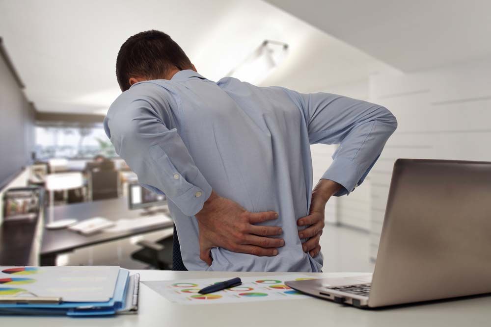 Man in Office, Holding His Lower Back — My Chiropractor Mackay City in Mackay, QLD