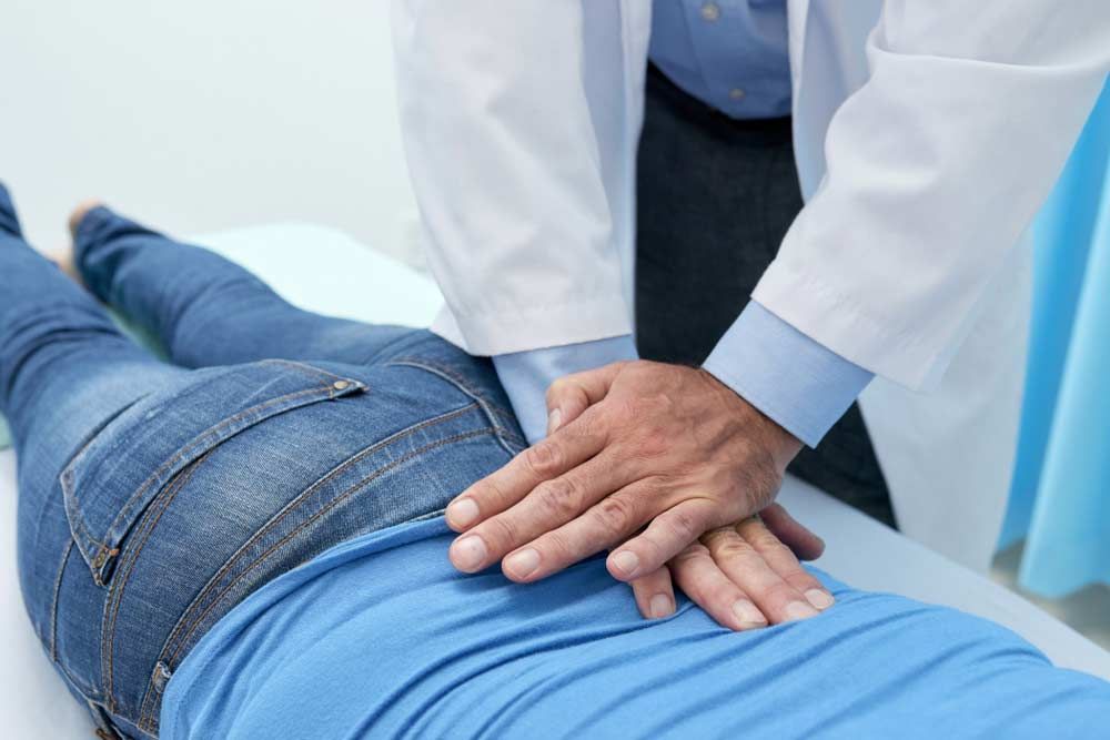 Doctor Pressing on Patient's Lower Back During an Examination — My Chiropractor Mackay City in Mackay, QLD
