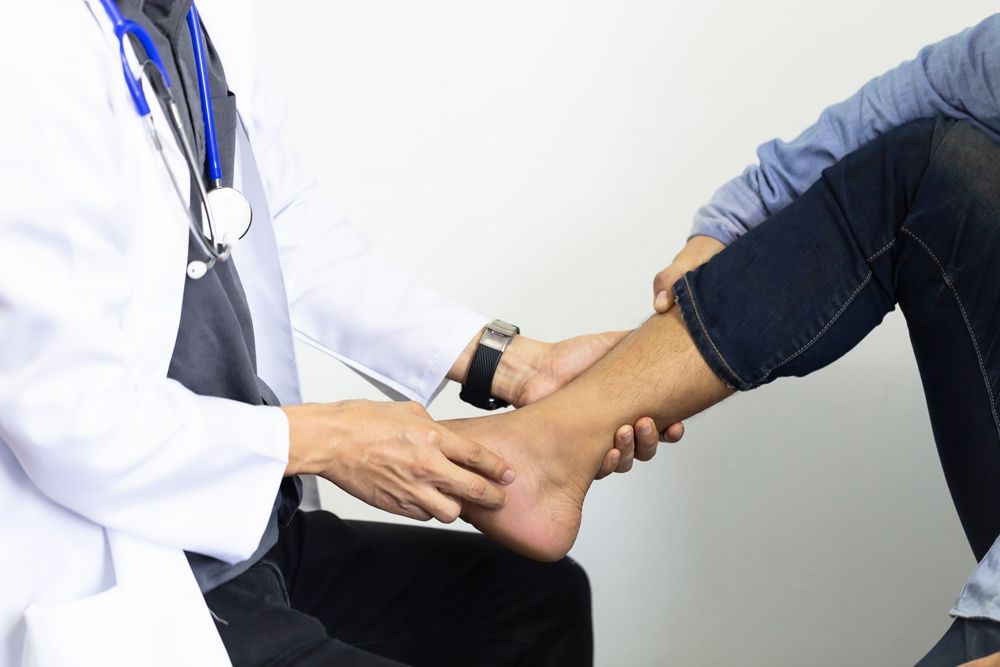 Doctor Examining a Patient's Ankle; White Coat, Stethoscope — My Chiropractor Mackay City in Mackay, QLD